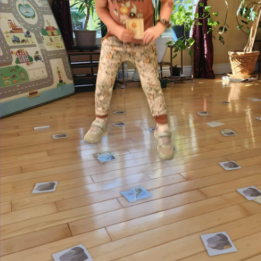 Enfant en mouvement qui saute d’une carte à l’autre pendant le jeu collaboratif Mission Dinosaures.